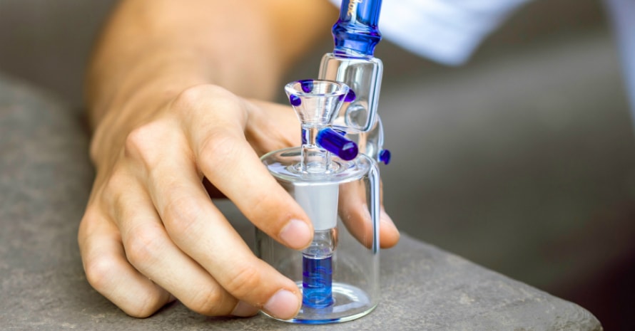 hand holds bong on the table